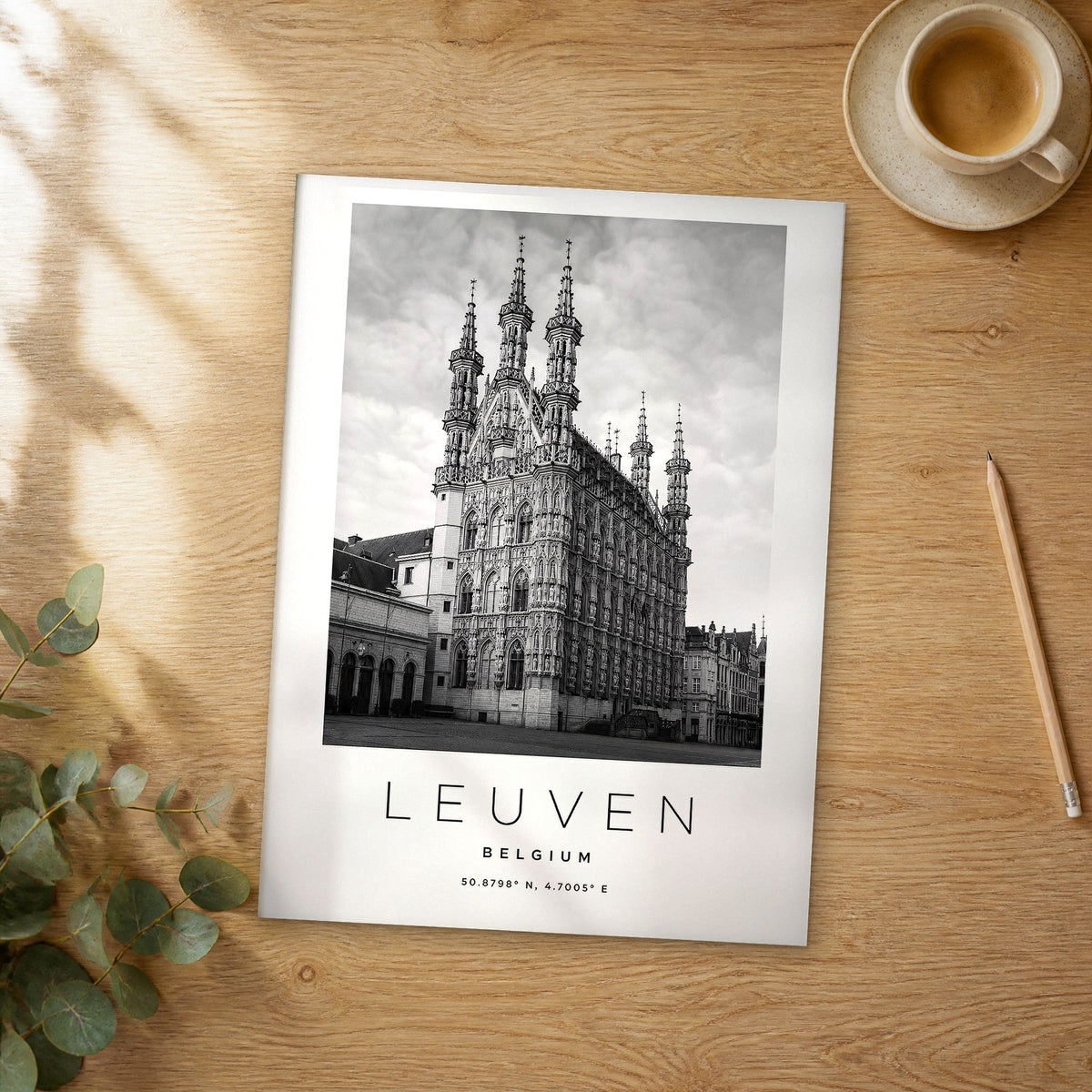 Unframed Leuven black and white travel poster on a wooden table