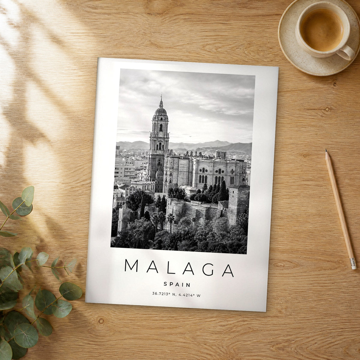 Unframed Malaga black and white travel poster on a wooden table