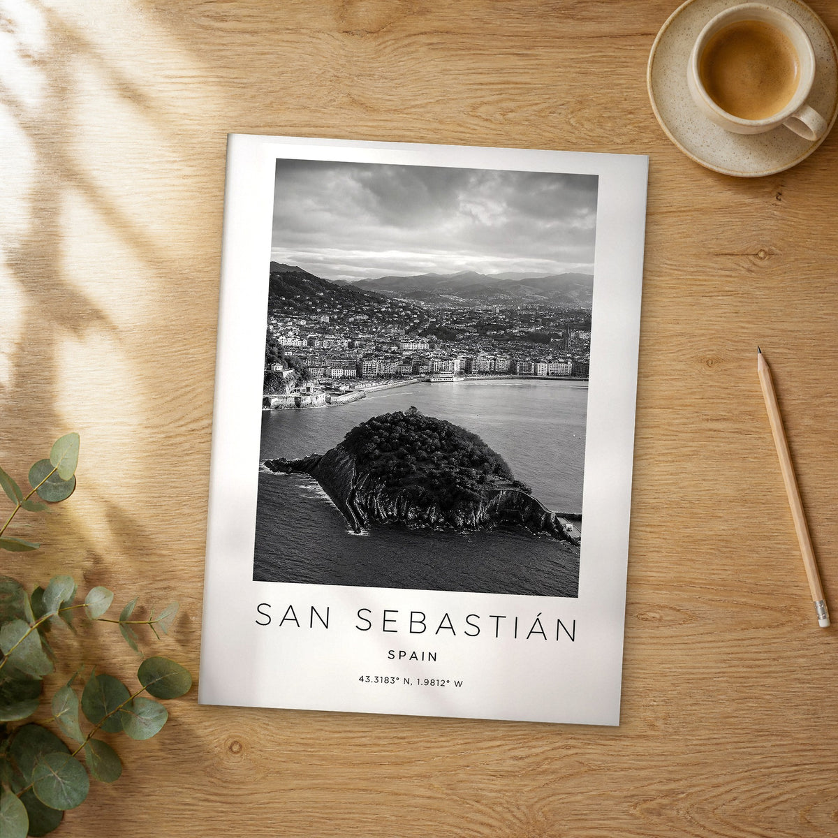Unframed San Sebastián black and white travel poster on a wooden table