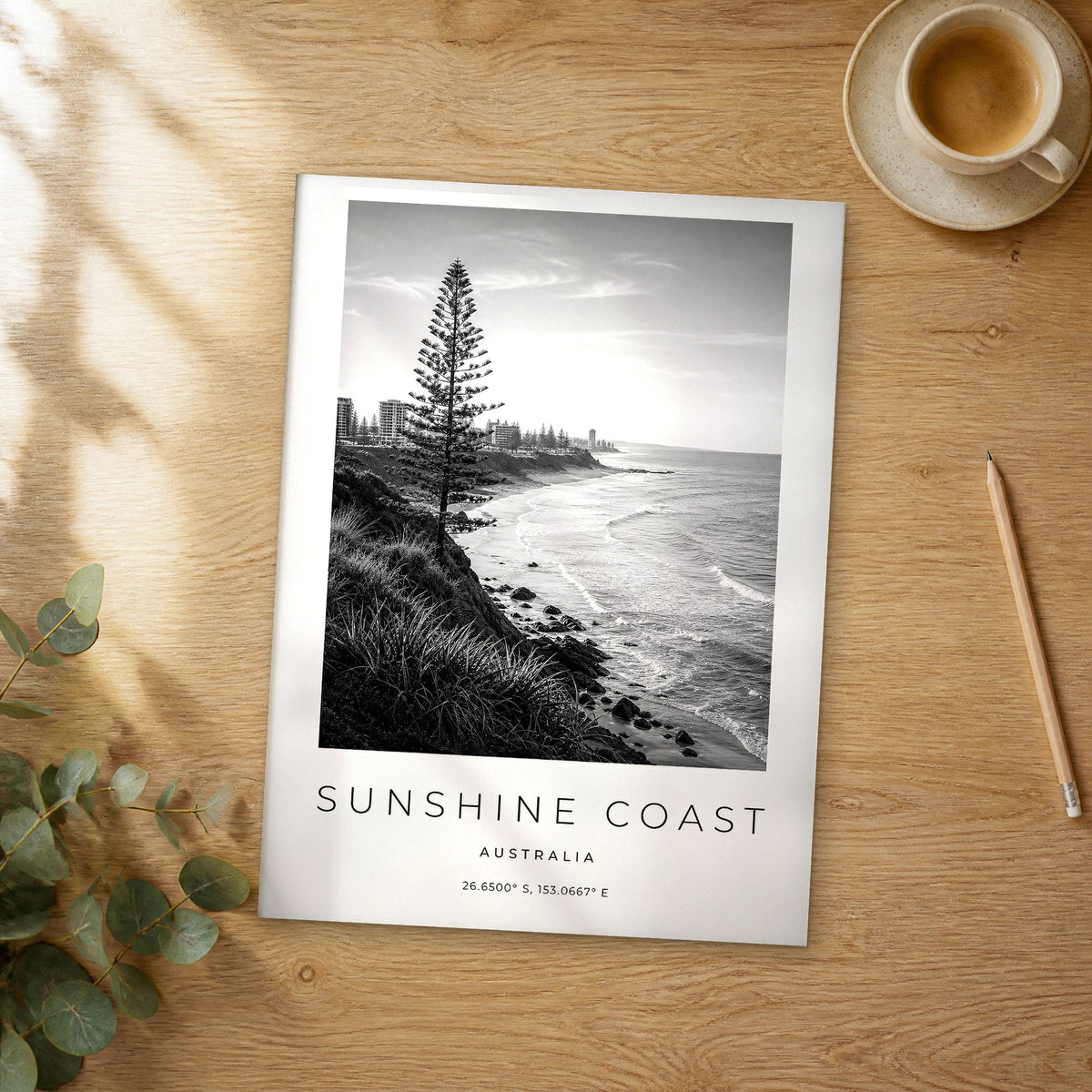 Unframed Sunshine Coast black and white travel poster on a wooden table