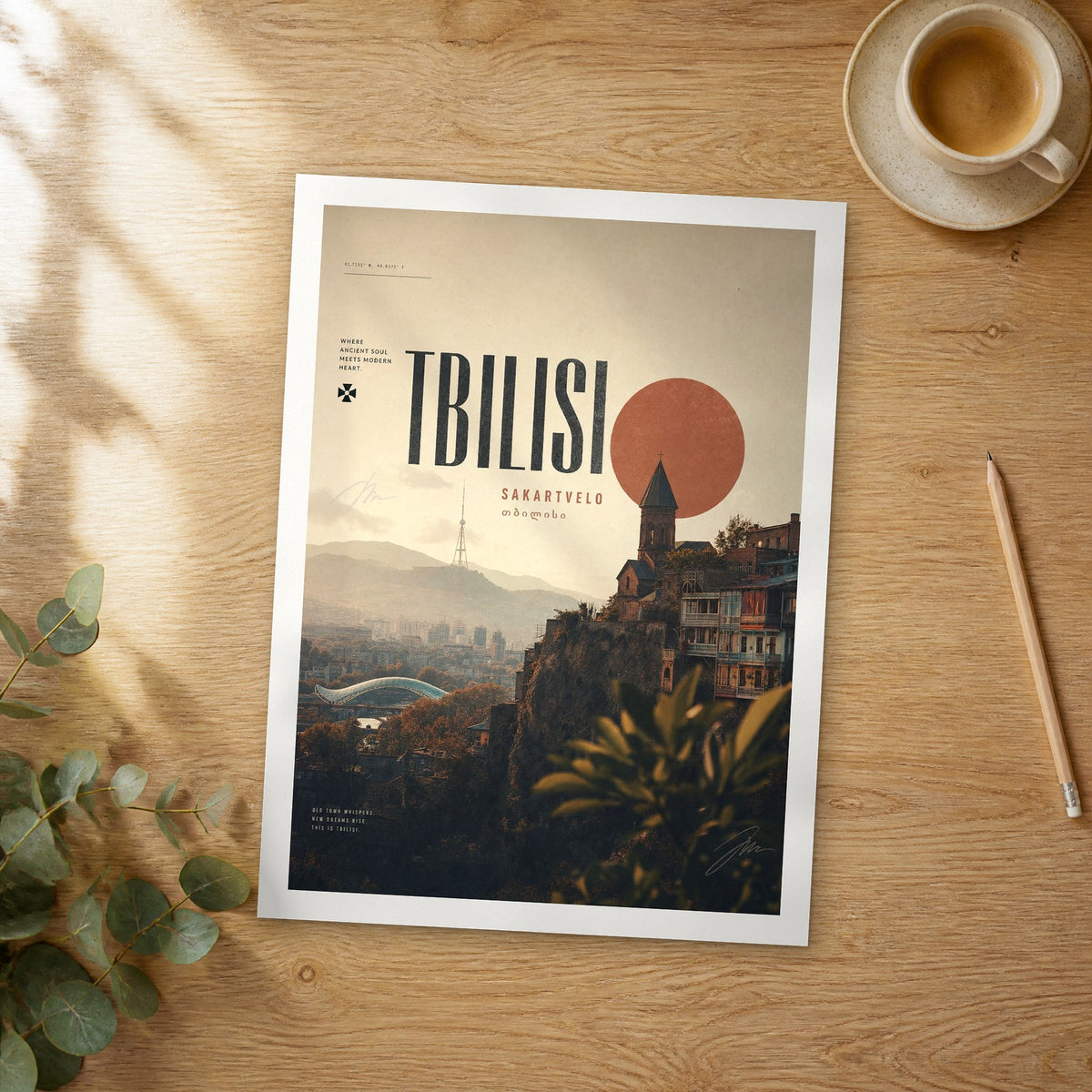 Unframed Tbilisi Cliffside Houses bold typography travel poster on a wooden table