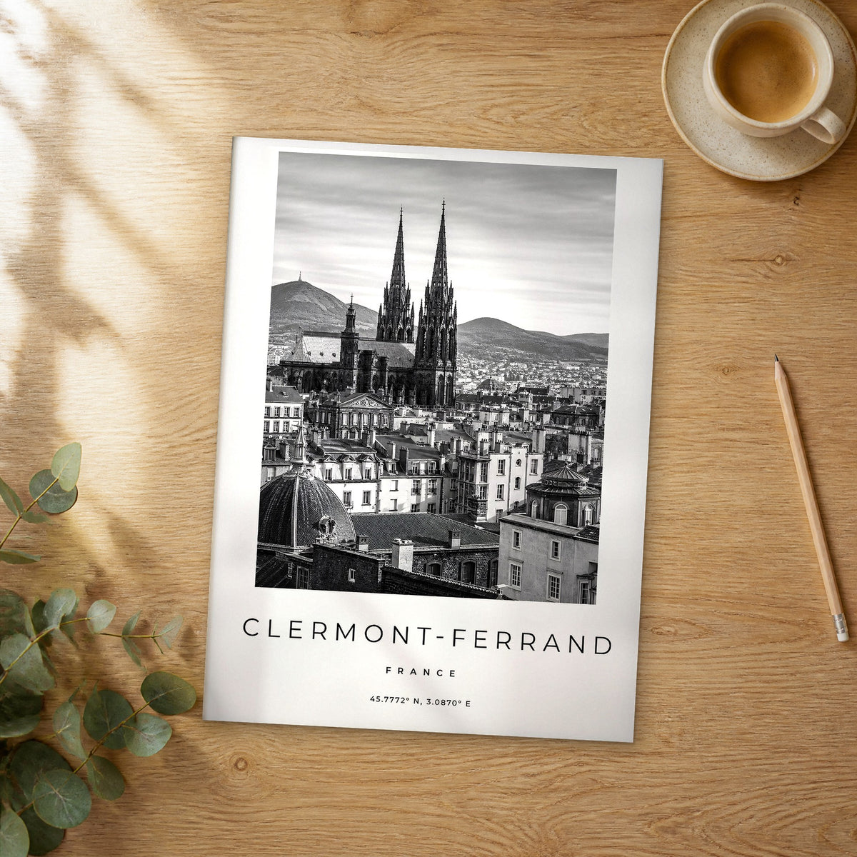Unframed Clermont-Ferrand black and white travel poster on a wooden table