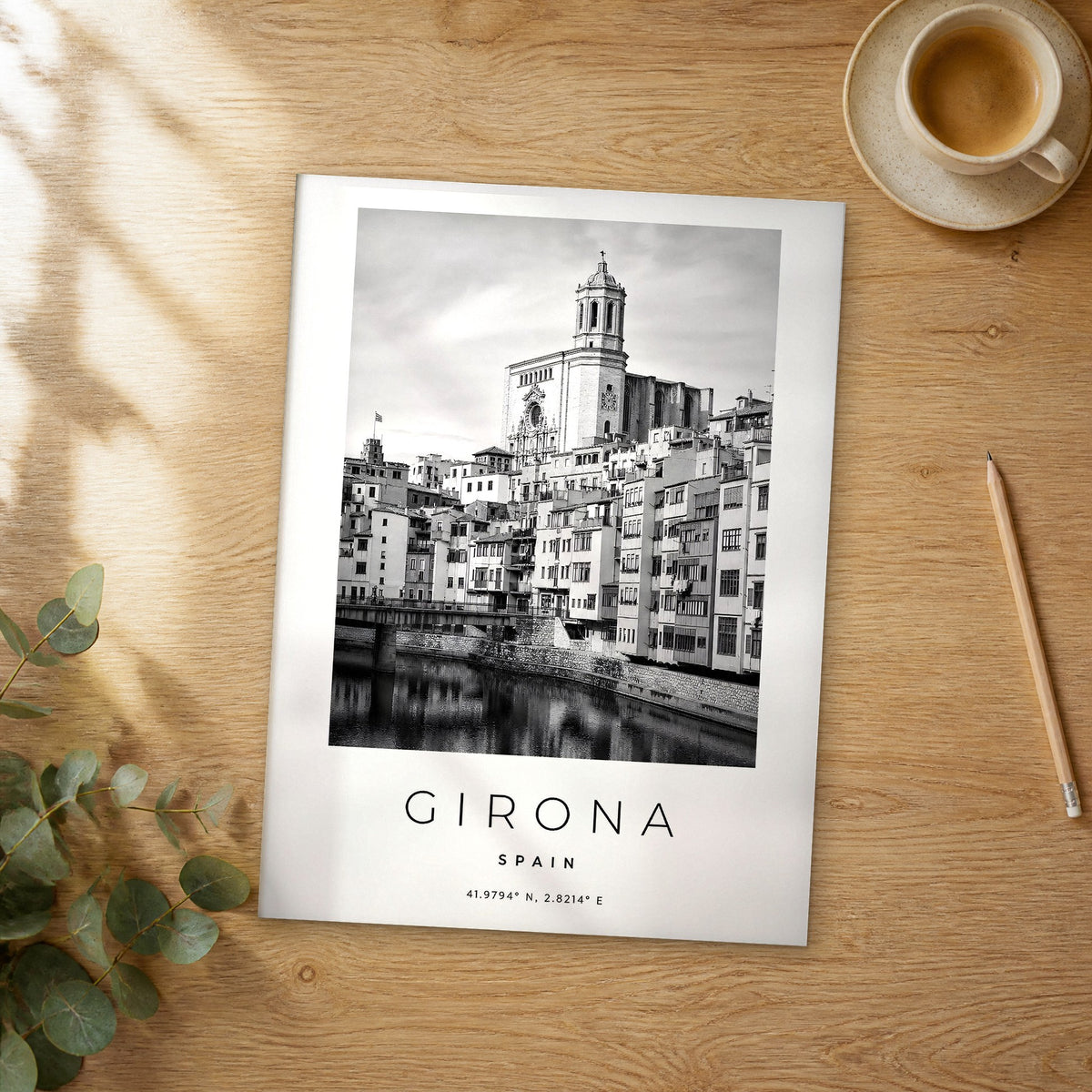 Unframed Girona black and white travel poster on a wooden table