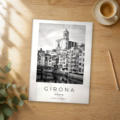 Unframed Girona black and white travel poster on a wooden table