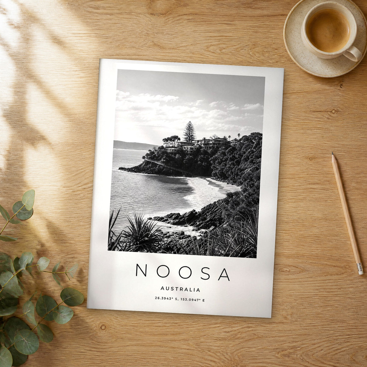 Unframed Noosa black and white travel poster on a wooden table