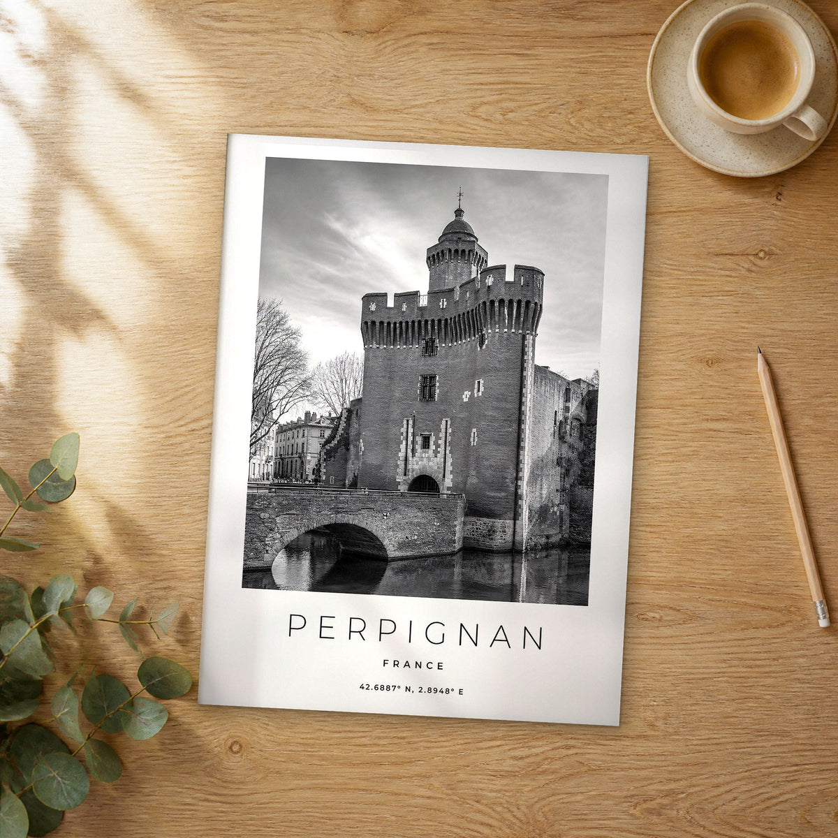 Unframed Perpignan black and white travel poster on a wooden table