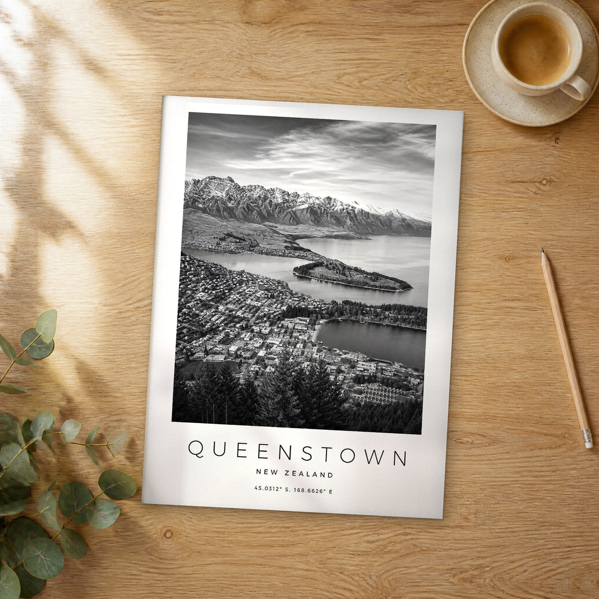 Unframed Queenstown black and white travel poster on a wooden table