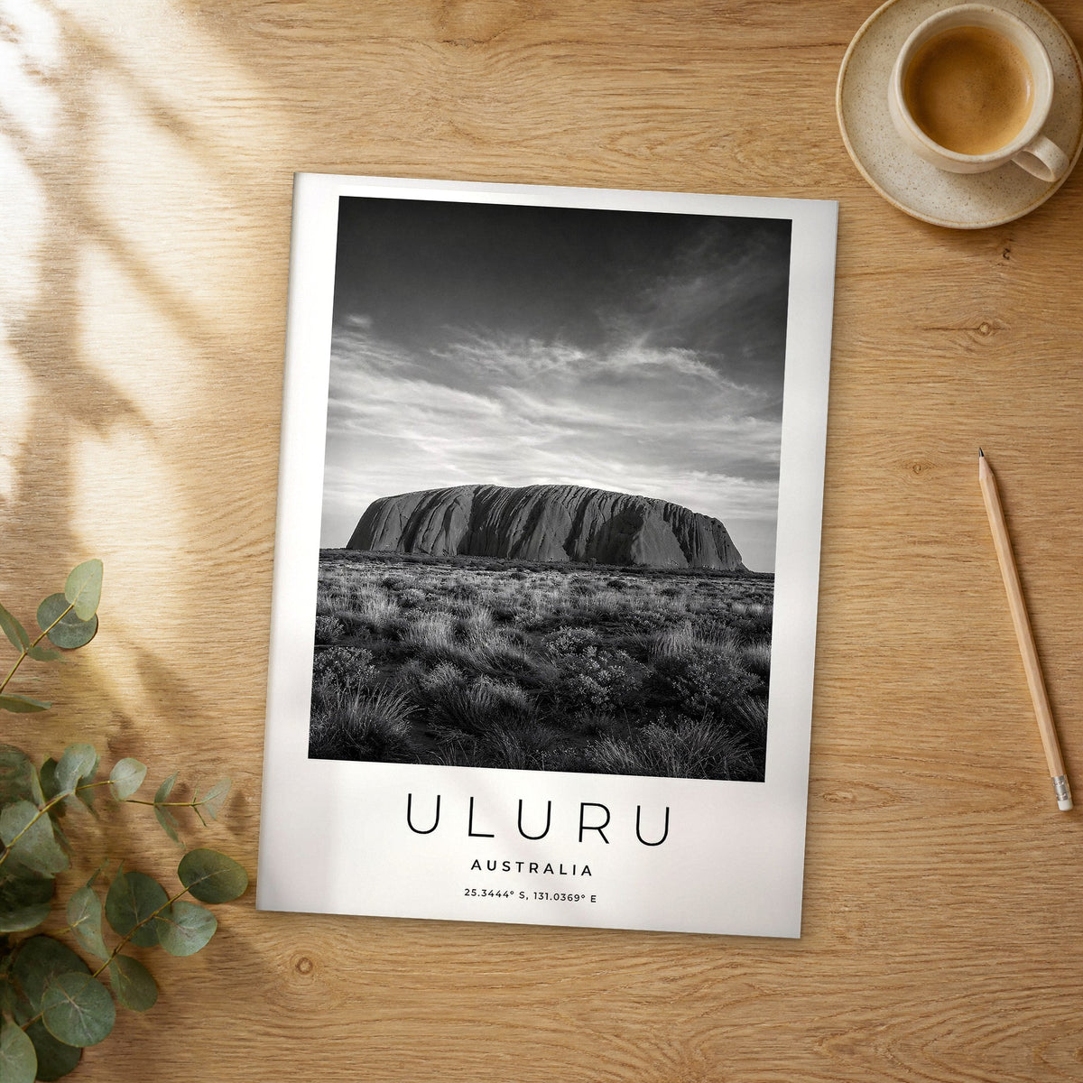 Unframed Uluru black and white travel poster on a wooden table